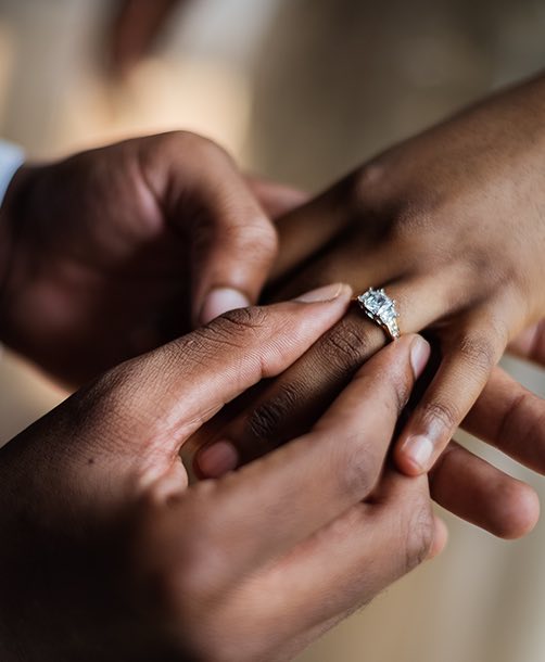 a man putting a diamond ring on a woman's finger